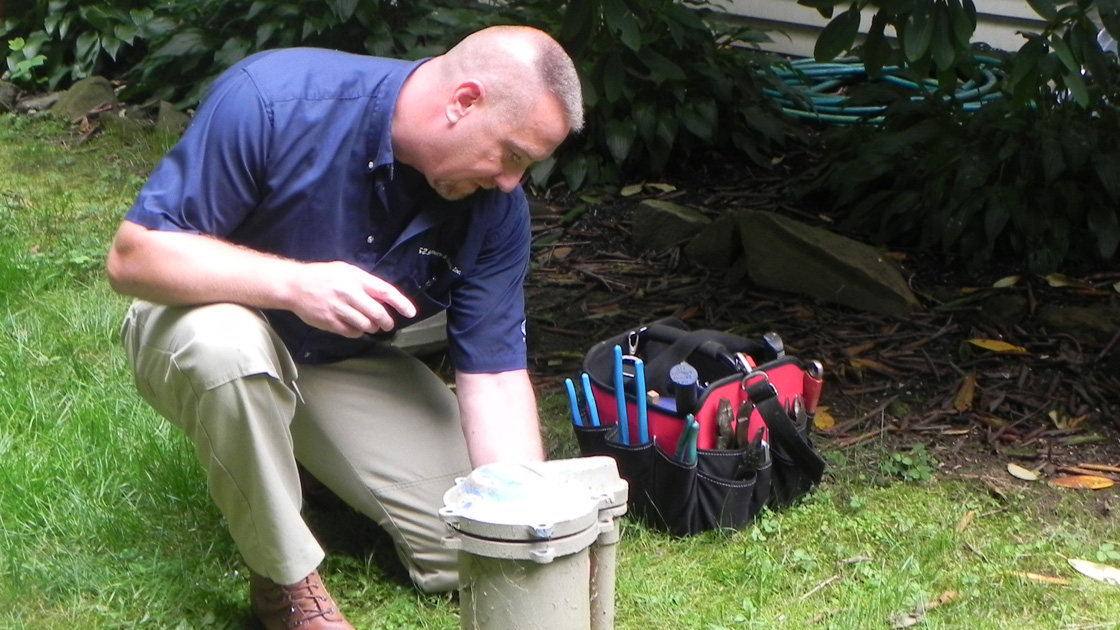 A plumbing professional in Lancaster, PA, servicing an outdoor well system.