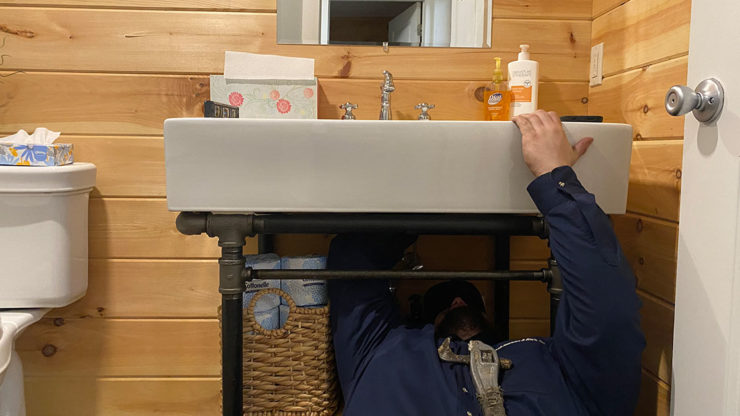 Skilled plumber repairing a water leak under a sink in a Pennsylvania home