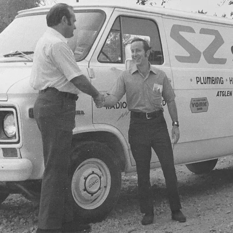 Founders of Summers and Zims shaking hands in front of their first service van.