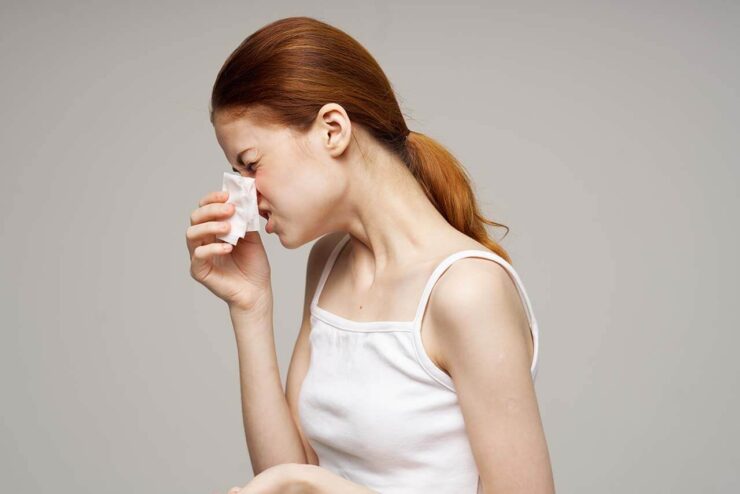 Red-haired woman holding a tissue, a common sign of dry indoor air-related discomfort.