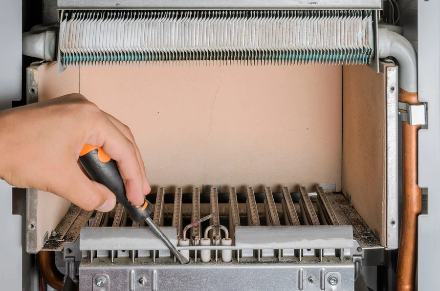 hand-using-screwdriver-on-furnace-burner-assembly-during-furnace-repair